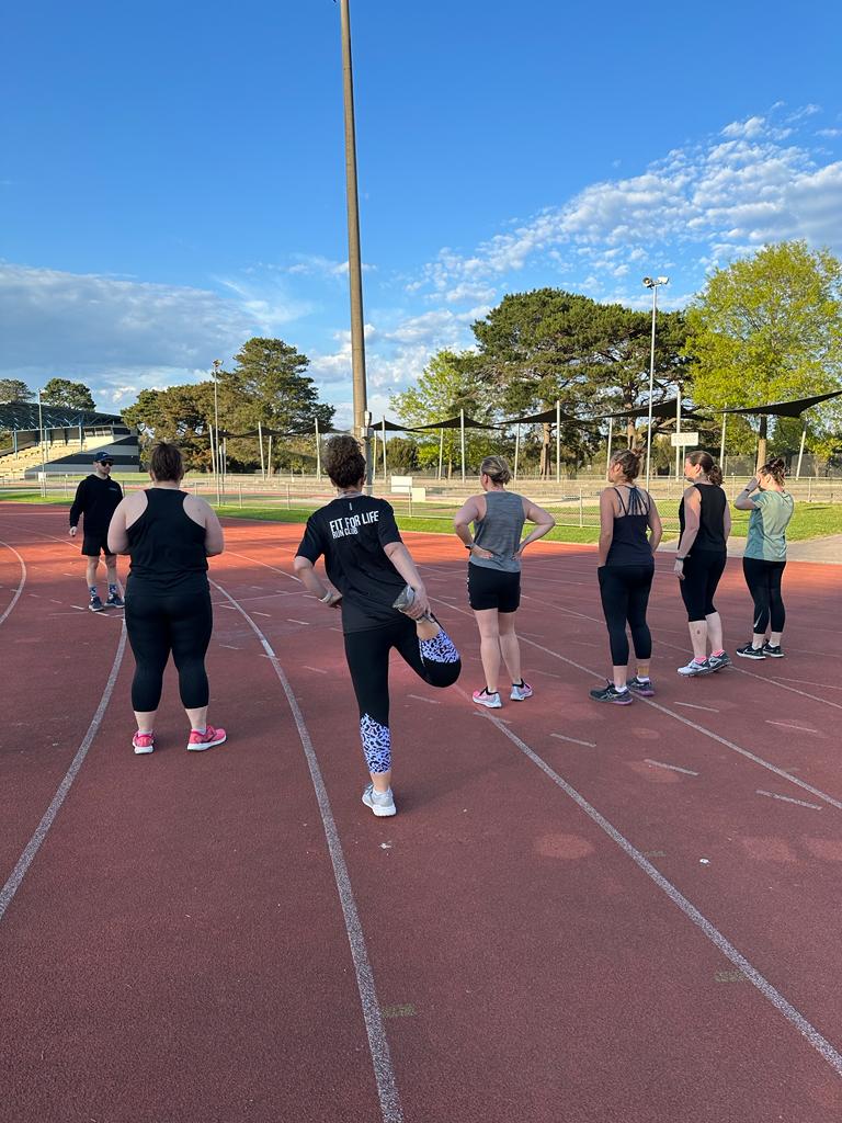 fit for life run club runners standing on an athletics track ahead of their running session